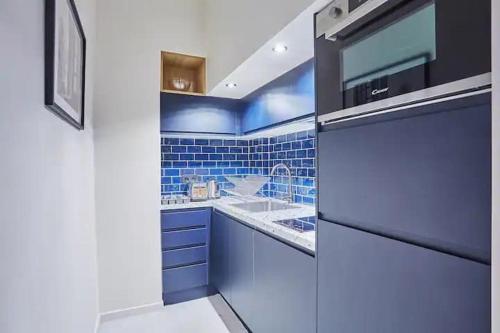 La cuisine bleue est équipée d'un évier et d'un réfrigérateur. dans l'établissement Charmant loft lumineux avec mezzanine Paris 11 - 4P - FLAT-GUEST, à Paris