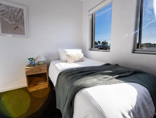 a white bedroom with a bed and two windows at Modern Townhouse, Close to beach in Christies Beach