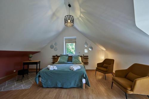 - une chambre mansardée avec un lit et deux chaises dans l'établissement Maison chaleureuse et spacieuse, à Bonot