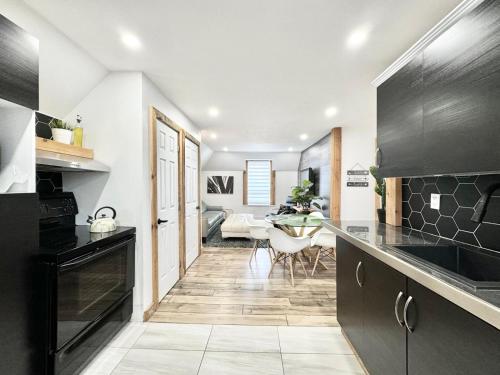 a kitchen with black cabinets and a dining room at Le Wolfe - 2 Bedrooms - 2 min Falls - Free Parking in Boischâtel