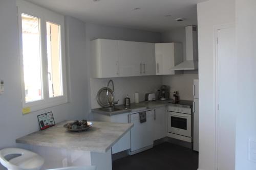 une cuisine avec des armoires blanches et un comptoir dans l'établissement L'ensoleillée Appartement Maison privé Cannes, à Cannes
