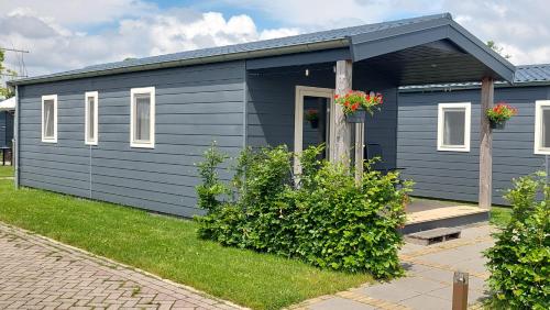 a blue tiny house with flowers in a yard at Chalet 4, Recreatie aan de Vecht in Weesp