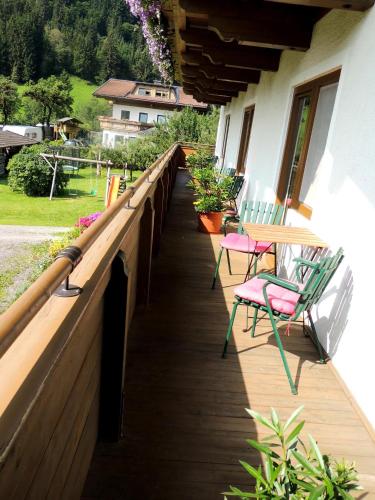 a wooden deck with chairs and a table on it at Pension Forsthof in Maishofen