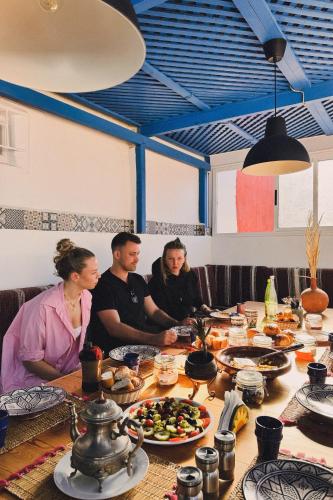 a group of people sitting at a table with food at El MOJA SURFHOUSE in Sidi Ifni