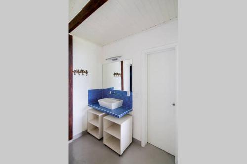 uma casa de banho com um lavatório azul num quarto branco em Sol-lua Bangalo com uso exclusivo da piscina em Ilhabela