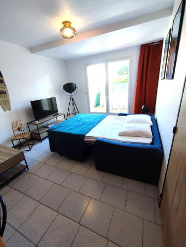 - une chambre avec un lit doté de draps bleus et d'une fenêtre dans l'établissement Appartement du port, à Saint-Cyprien