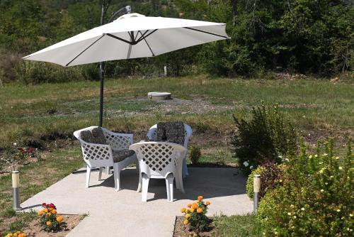 a table and two chairs under an umbrella at Šarganska Idila in Mokra Gora