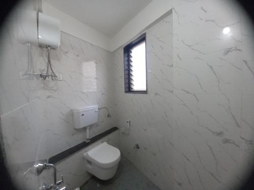 a white bathroom with a toilet and a window at Hotel Highway Palace in Nashik