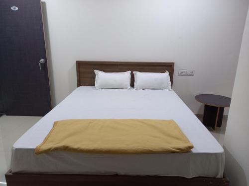 a bedroom with a bed with a yellow blanket on it at Hotel Highway Palace in Nashik