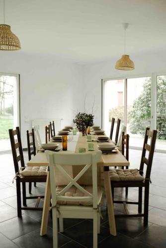 une table à manger avec des chaises et une longue table fleurie dans l'établissement Gite Groupe - parc Château de la Pinais, à Moisdon-la-Rivière