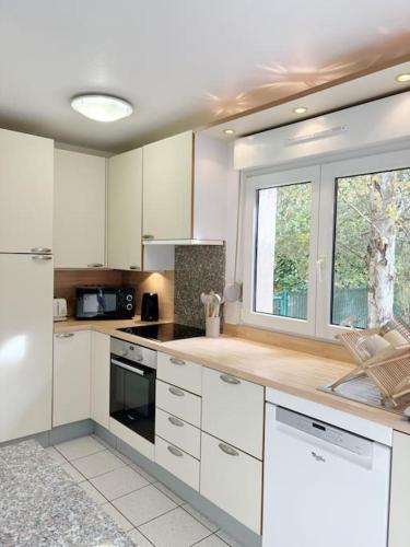 une grande cuisine avec des armoires blanches et une fenêtre dans l'établissement La petite Luss, à Colmar