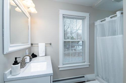 a white bathroom with a sink and a window at Updated Family-sized Home in Heart of Rutland, Near Slopes, EV Level 2, Hot Tub in Rutland