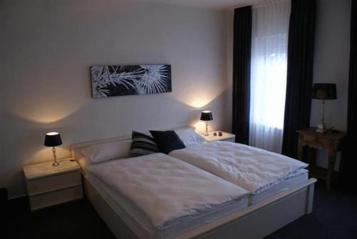 a bedroom with a large bed with two tables and two lamps at Hotel Stadt Coblenz in Fachbach