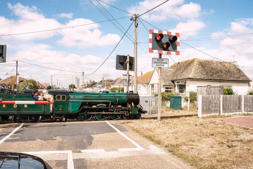 a small green train traveling down the tracks at Pass the Keys Dungeness Drift - By the Beach in Folkestone