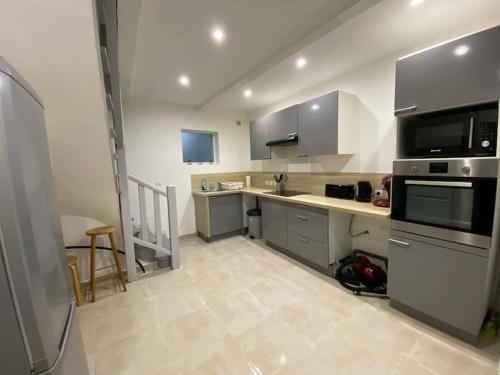 - une grande cuisine avec des appareils électroménagers en acier inoxydable et des murs blancs dans l'établissement Maison de village, à Montpezat