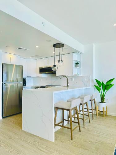 a kitchen with white cabinets and a counter with stools at Panoramic Oceanview Resort - Full Kitchen in Each Unit, 2 Swimming Pools, Onsite Restaurants, Fireworks Every Friday in Honolulu