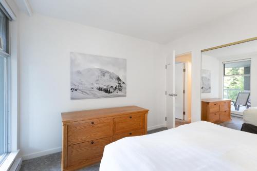 a bedroom with a bed and a dresser and a window at The Woodrun Lodge by Whiski Jack in Whistler
