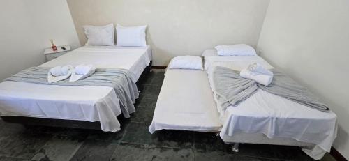 two beds in a room with white towels on them at Pousada Terra Do Sol in Arraial do Cabo
