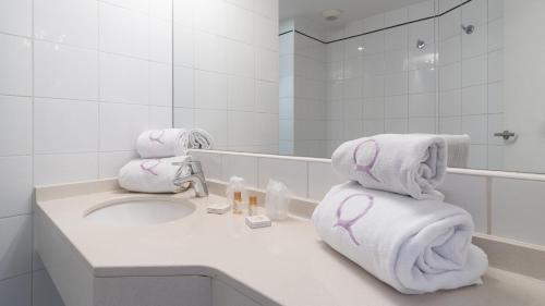a bathroom with towels on a sink and a mirror at Hôtel Ours Blanc - Centre in Toulouse