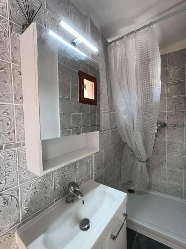 une salle de bain avec un lavabo, un miroir et une baignoire dans l'établissement Le nid douillet au cœur du village, à Sainte-Agnès