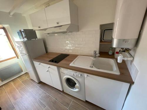 une cuisine avec une machine à laver et un évier dans l'établissement Le nid douillet au cœur du village, à Sainte-Agnès
