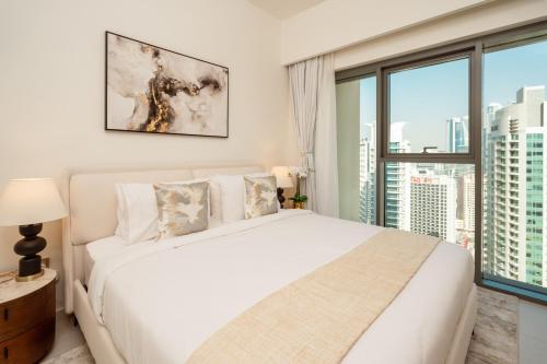 een slaapkamer met een wit bed en een groot raam bij Prime Retreats @ Burj Royale By Emaar in Dubai