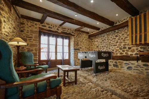 - un salon avec une cheminée dans un mur en pierre dans l'établissement Jolie maison deux chambres et canapé-lit #au cœur du village#, à Sainte-Eulalie-dʼOlt