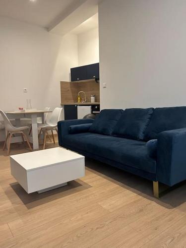 un salon avec un canapé bleu et une table dans l'établissement Appartement T2 - Chalon-sur-Saône, à Chalon-sur-Saône