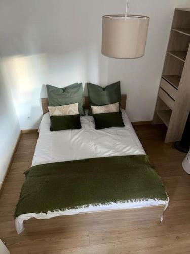 - un lit avec des oreillers et une couverture verts dans l'établissement Appartement T2 - Chalon-sur-Saône, à Chalon-sur-Saône