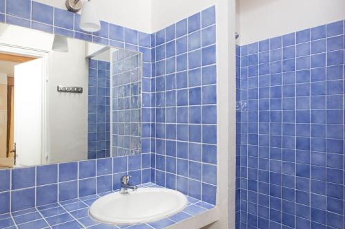 La salle de bains est pourvue de carrelage bleu, d'un lavabo et d'un miroir. dans l'établissement La petite maison des pins, à La Roquette-sur-Siagne