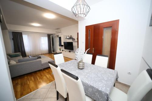 a dining room and living room with a table and chairs at Iva Lux stan na dan in Banja Luka
