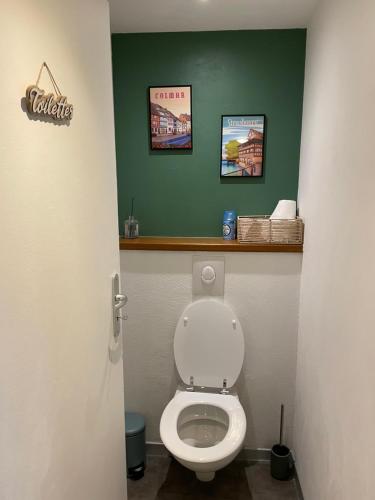 a bathroom with a toilet with two pictures on the wall at Le Cosy Green - centre-ville in Sélestat