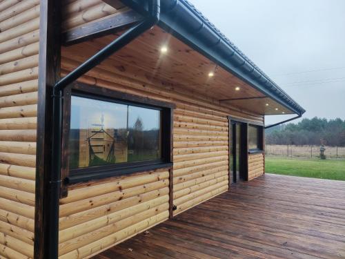 a log cabin with a large window on a deck at Leśny Wyraj in Borsuki