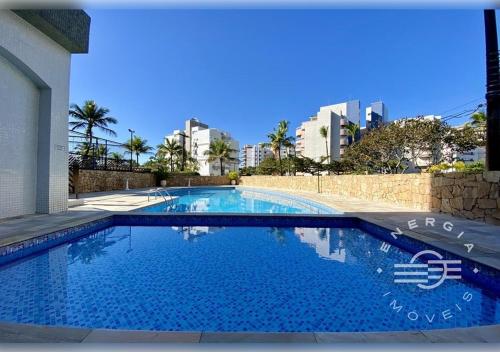 a large blue swimming pool with buildings in the background at Apto próximo a praia em Riviera in Bertioga