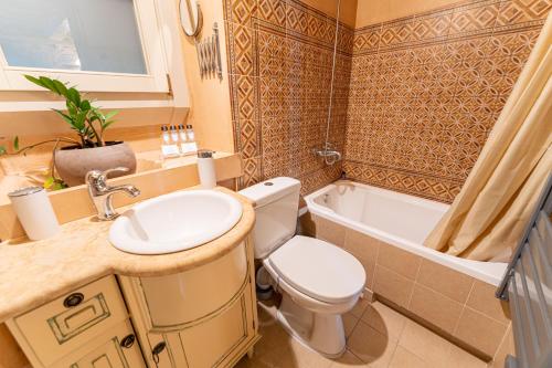 a bathroom with a toilet and a sink and a tub at Irene's Mansion in Vrontados