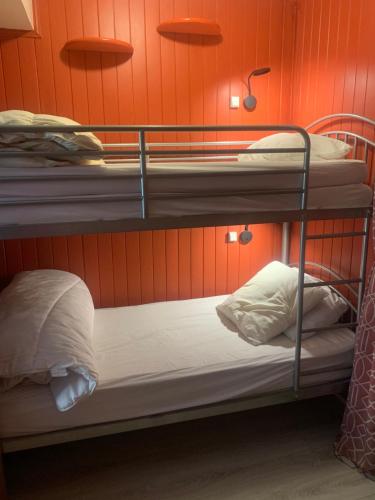 Ce lit se trouve dans un dortoir doté de 2 lits superposés et d'un mur orange. dans l'établissement Studio Isola 2000 centre station front de neige, à Isola