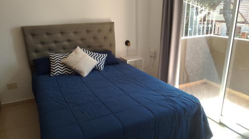 a bed with a blue comforter and pillows in a bedroom at Departamento a estrenar GALO VII in San Bernardo