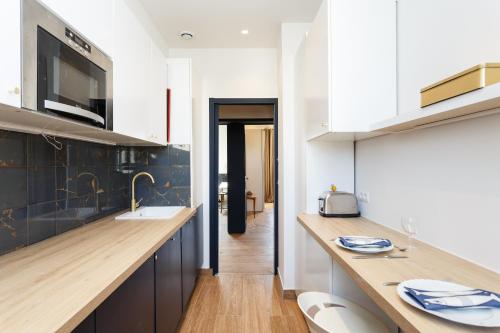 une cuisine avec des armoires blanches et un comptoir en bois dans l'établissement La belle vie à 7 minutes à pied du Stade de France, à Saint-Denis