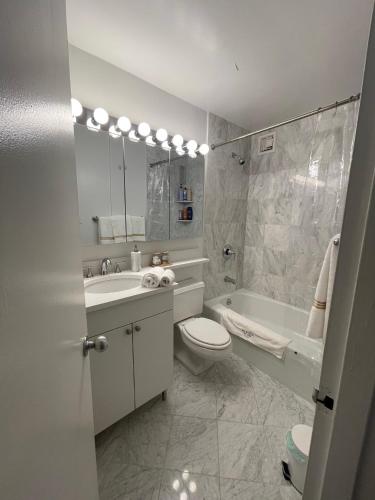 a bathroom with a toilet and a sink and a tub at Nomad stylish studio in NYC in New York