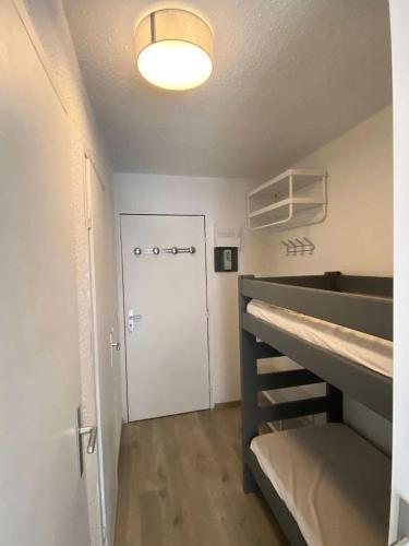 Cette petite chambre comprend des lits superposés et une porte. dans l'établissement Résidence Le Cairn - Coquet studio 4 personnes MAE-6741, aux Orres