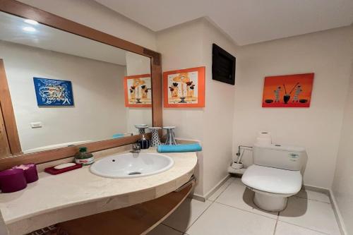 a bathroom with a sink and a toilet and a mirror at Appartement Bahia Golf Beach Bouznika,Plage & Golf in Bouznika