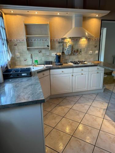 Il comprend une grande cuisine avec des placards blancs et du carrelage. dans l'établissement Shelby house, à Prémery