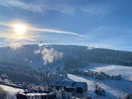 a snow covered mountain with the sun in the sky at Horská chata LADA in Loučná pod Klínovcem