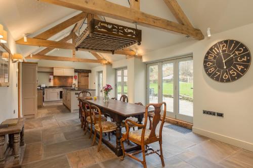 a kitchen with a wooden table and a large clock on the wall at Scugdale Cottage - Hartoft in Pickering