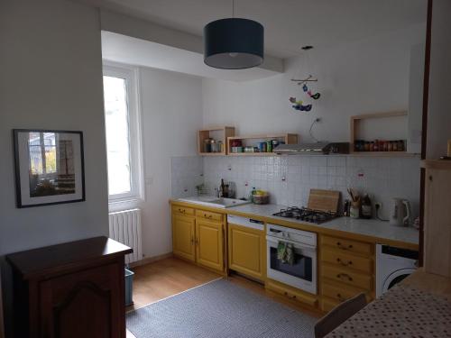 - une cuisine avec des armoires jaunes et un four avec plaques de cuisson dans l'établissement Les Coustous, à Bagnères-de-Bigorre