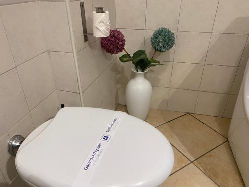 a white toilet in a bathroom with a vase with flowers at Bilocale degli Innamorati in Terni