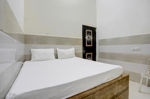 a bedroom with a large bed with white sheets at Hotel O YOUR RESIDENCY in Ghaziabad