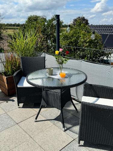 a glass table with a vase of flowers on a patio at Ferienwohnung Weitblick in Erftstadt