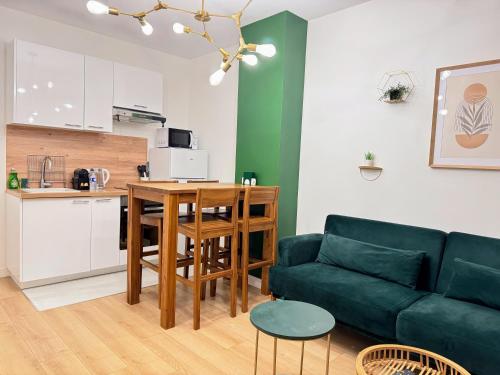 a living room with a couch and a table and a kitchen at Le Vertueux - CDG - Parking - Confort - Wifi in Louvres