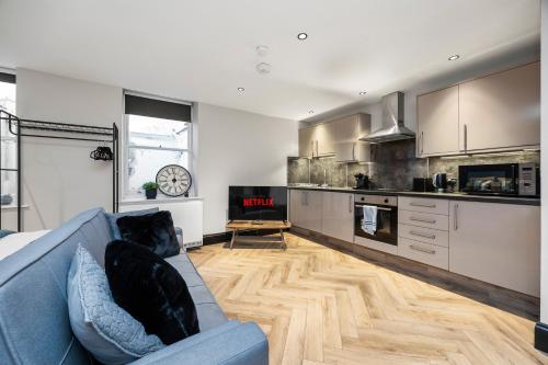 a living room with a blue couch and a kitchen at Central Luxe - Brighton Central - 2 Beds in Brighton & Hove
